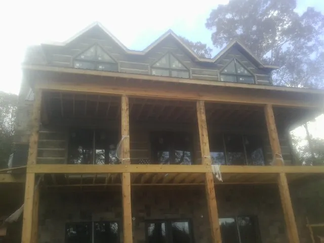 Dormers and porch framing on a large log home under construction — Roof Coating work by our crew in South Salem