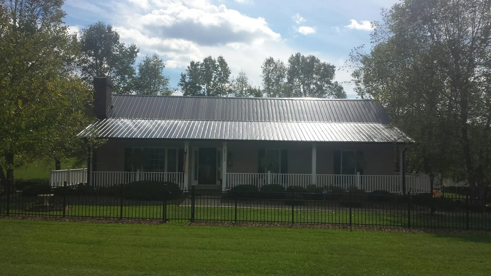 Gray metal roof on a brick ranch with a full width front porch — Gutter Guard Installation work by our crew in South Salem