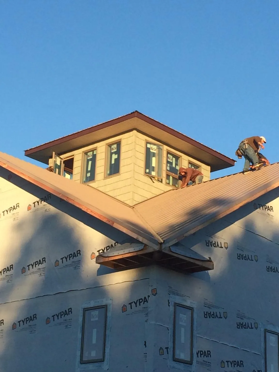Roofers working around a rooftop cupola on a new metal roof at sunset — Roof Waterproofing in South Salem by Roofing Brothers